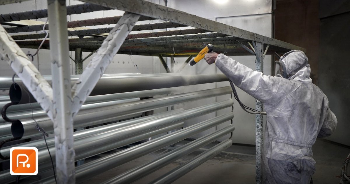Paints & Coatings Wholesale Suppliers UAE B2B 2026 - worker in protective gear applying powder coating to metal pipes